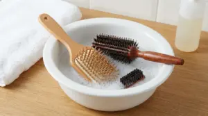 Spazzole per capelli in ammollo in una bacinella con acqua e sapone per igienizzarle in casa