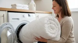 Donna che cerca di inserire un piumone voluminoso nella lavatrice di casa