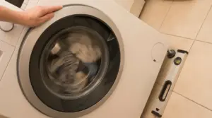 Persona che controlla il livello di una lavatrice mentre centrifuga, per ridurre vibrazioni e rumore