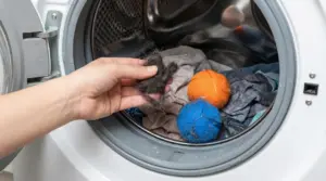 Mano che mostra peli raccolti dal bucato in lavatrice con palline cattura peli tra i vestiti