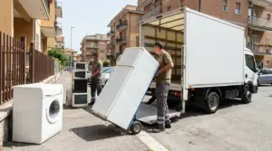 Addetti caricano un frigorifero e vecchi elettrodomestici su un furgone per il ritiro a domicilio in città