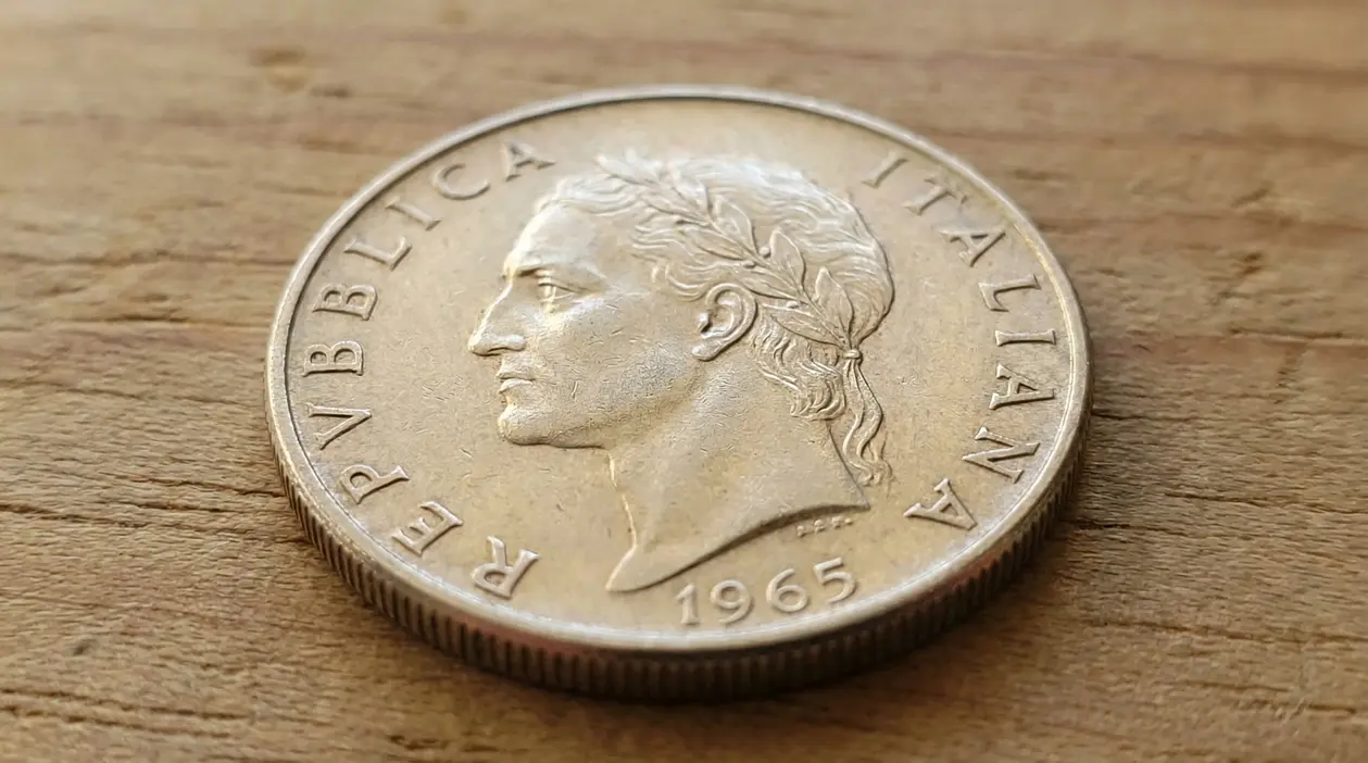 Moneta da 500 lire italiana del 1965 appoggiata su una superficie di legno