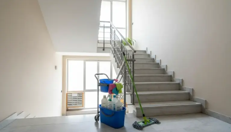 Vano scale condominiale con carrello delle pulizie, secchio, detergenti e mop vicino ai gradini
